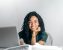 happy ethnic woman sitting at table with laptop